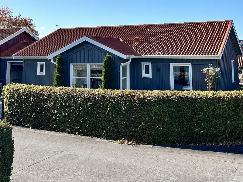 Nymålad grå träfasad med vita fönster och rött tegeltak