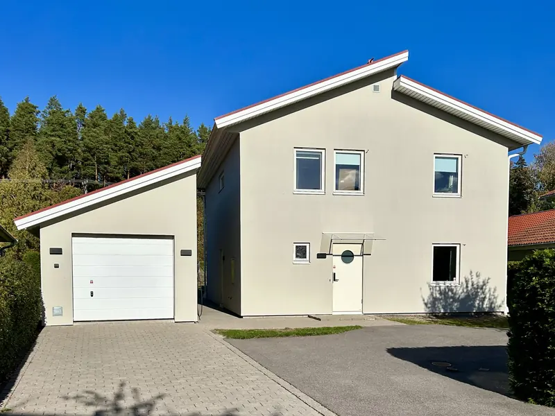 Putsad villa i Linköping med nymålad varmgrå fasad och rött tegeltak